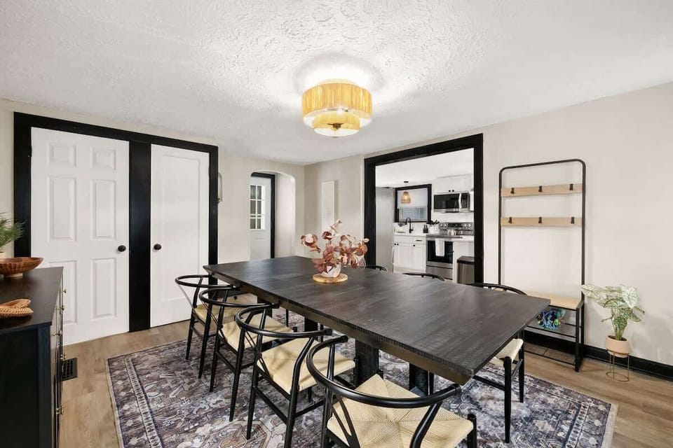 Sophisticated dining room w/ dark table, patterned rug & elegant lighting