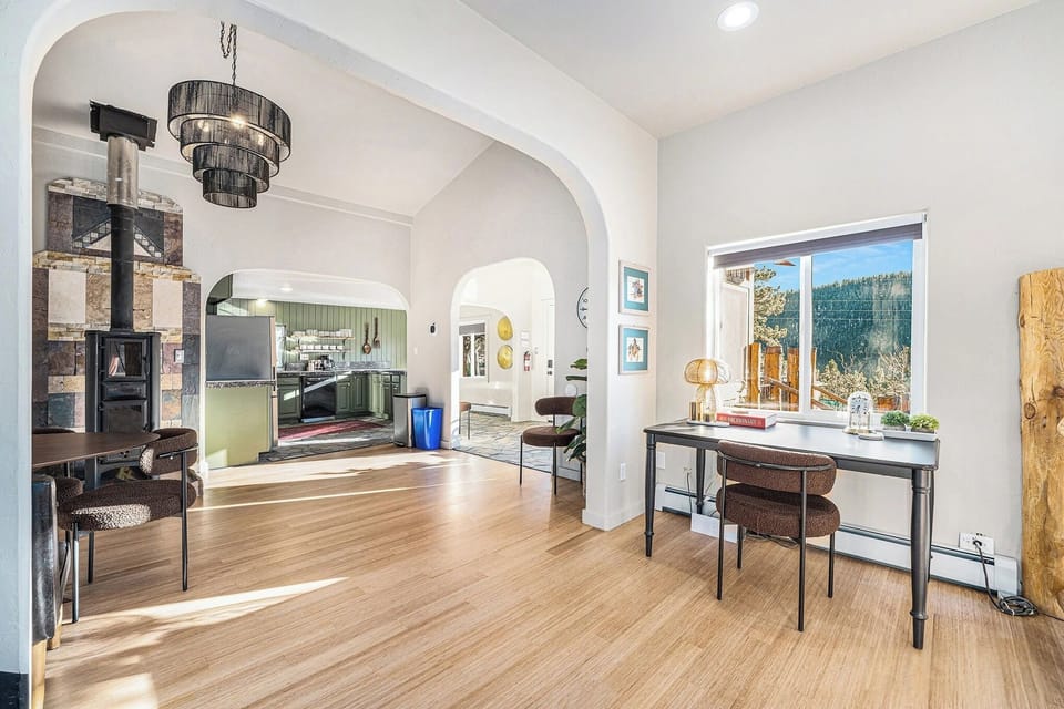 - Find inspiration at a sleek desk with a golden lamp and forest framed window
- Modern arches and layered lighting connect to a cozy, character filled kitchen
- Open layout with bamboo floors and eclectic decor for a warm, creative feel
