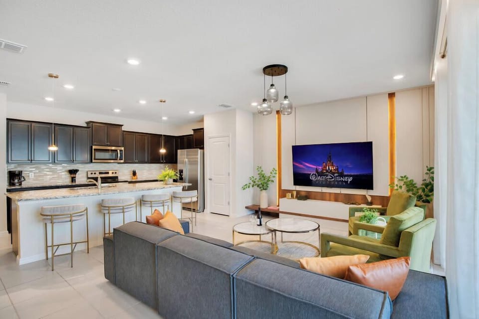 Modern open-concept living area with a large kitchen island and wall-mounted television.
