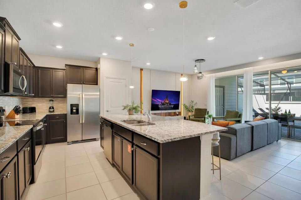 Modern kitchen with granite island open to a bright living area and outdoor patio