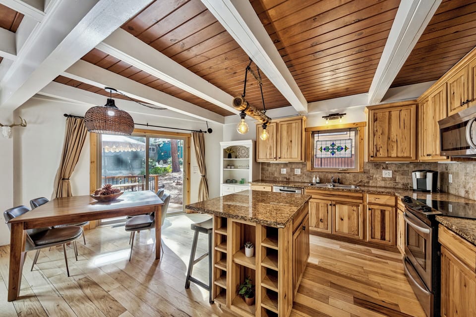 Gather around your rustic kitchen island where granite counters meet warm wood cabinetry, perfect for morning coffee or evening meal prep.