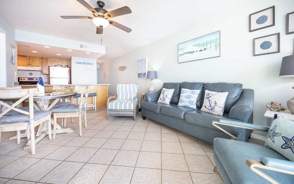 This inviting living area features a comfortable gray sofa, a dining table, and a view of the well-equipped kitchen