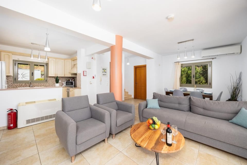 Open-plan living room with sofa, dining area, kitchen, ornamental fireplace, A/C, WiFi internet, and satellite TV