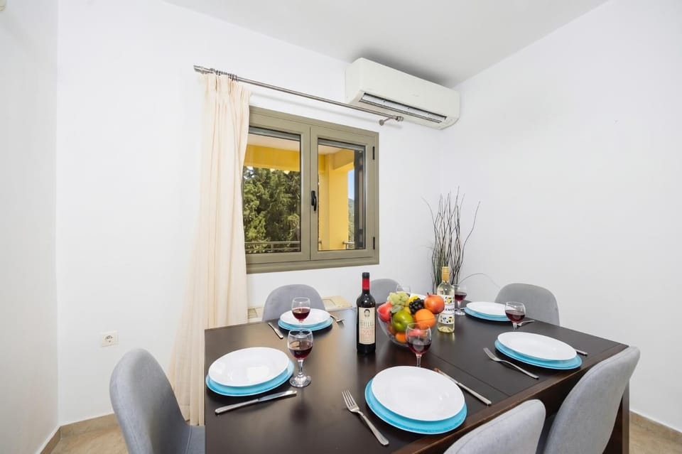 Open-plan living room with sofa, dining area, kitchen, ornamental fireplace, A/C, WiFi internet, and satellite TV