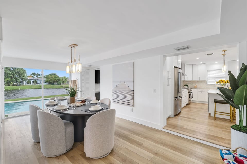 Share meals beside the waterway, with the dining area flowing naturally into the kitchen and opening toward the poolside views.
