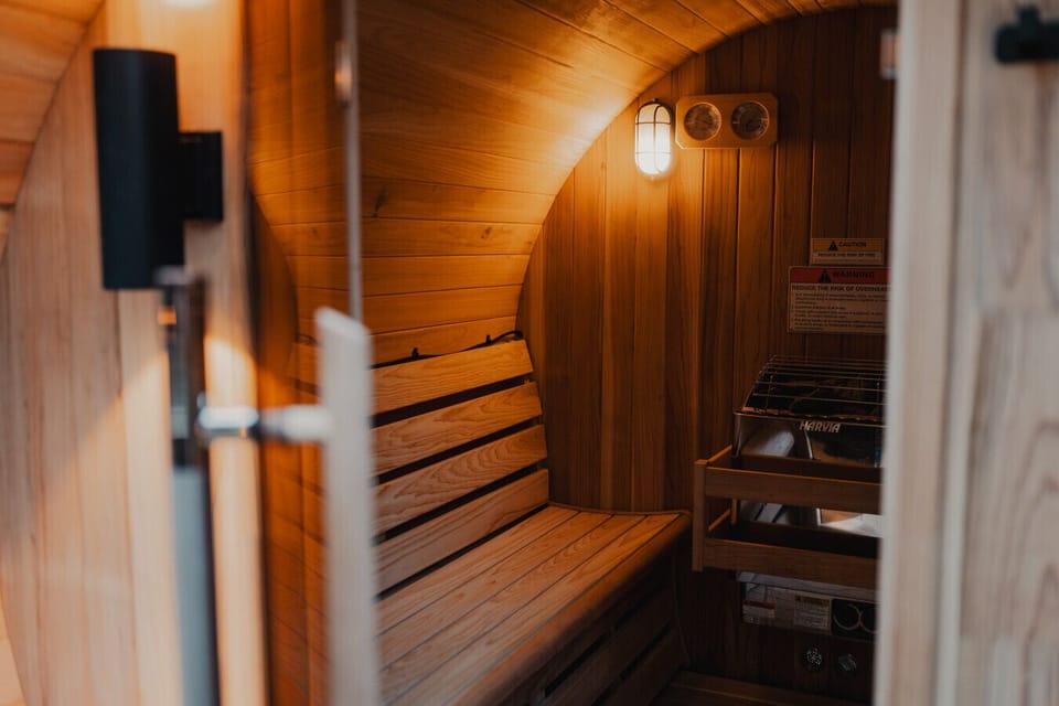 Warm, Inviting Sauna Experience – Step into a beautifully lit cedar sauna with soft ambient lighting and classic wood finishes—perfect for unwinding in total comfort.