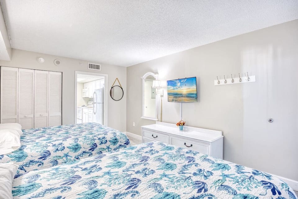 Bedroom Retreat: Bright and inviting room with two queen beds and beach-themed decor, perfect for rest!