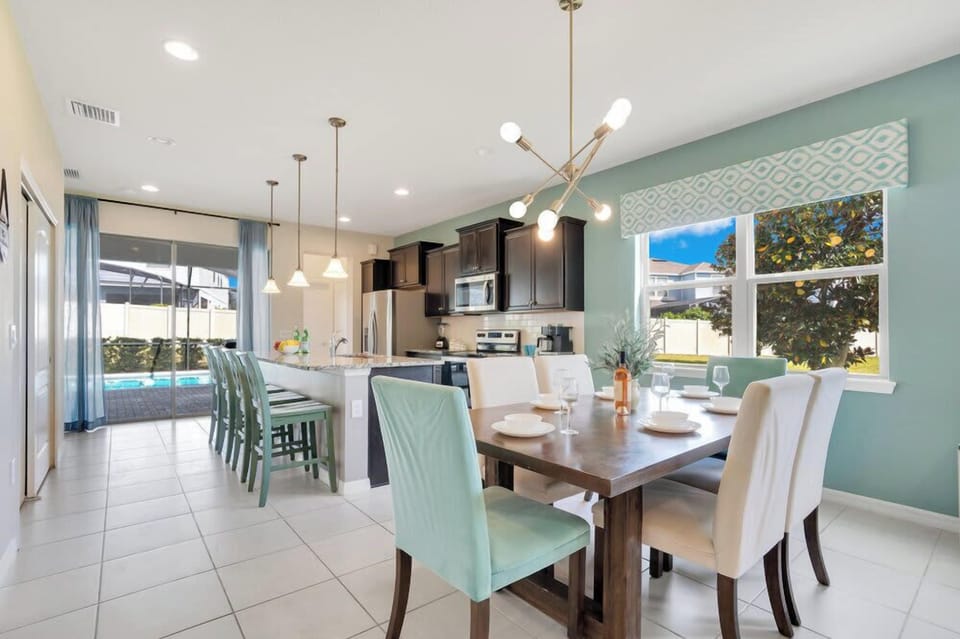 Modern kitchen and dining area with seating for eight and a view of the pool.
