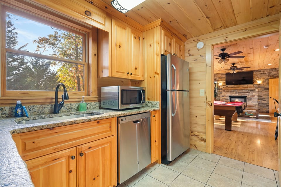 Cozy kitchen with modern appliances and a view into the game room and fireplace.