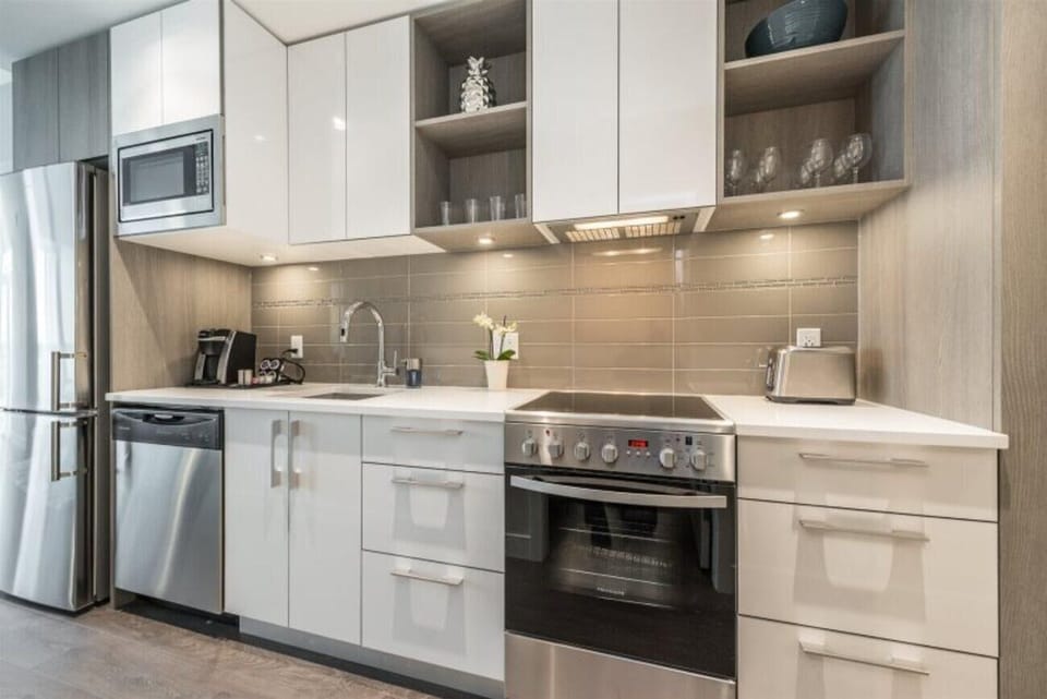 Modern kitchen galley equipped with full-sized stainless steel appliances, electric range, built-in microwave, and dishwasher.