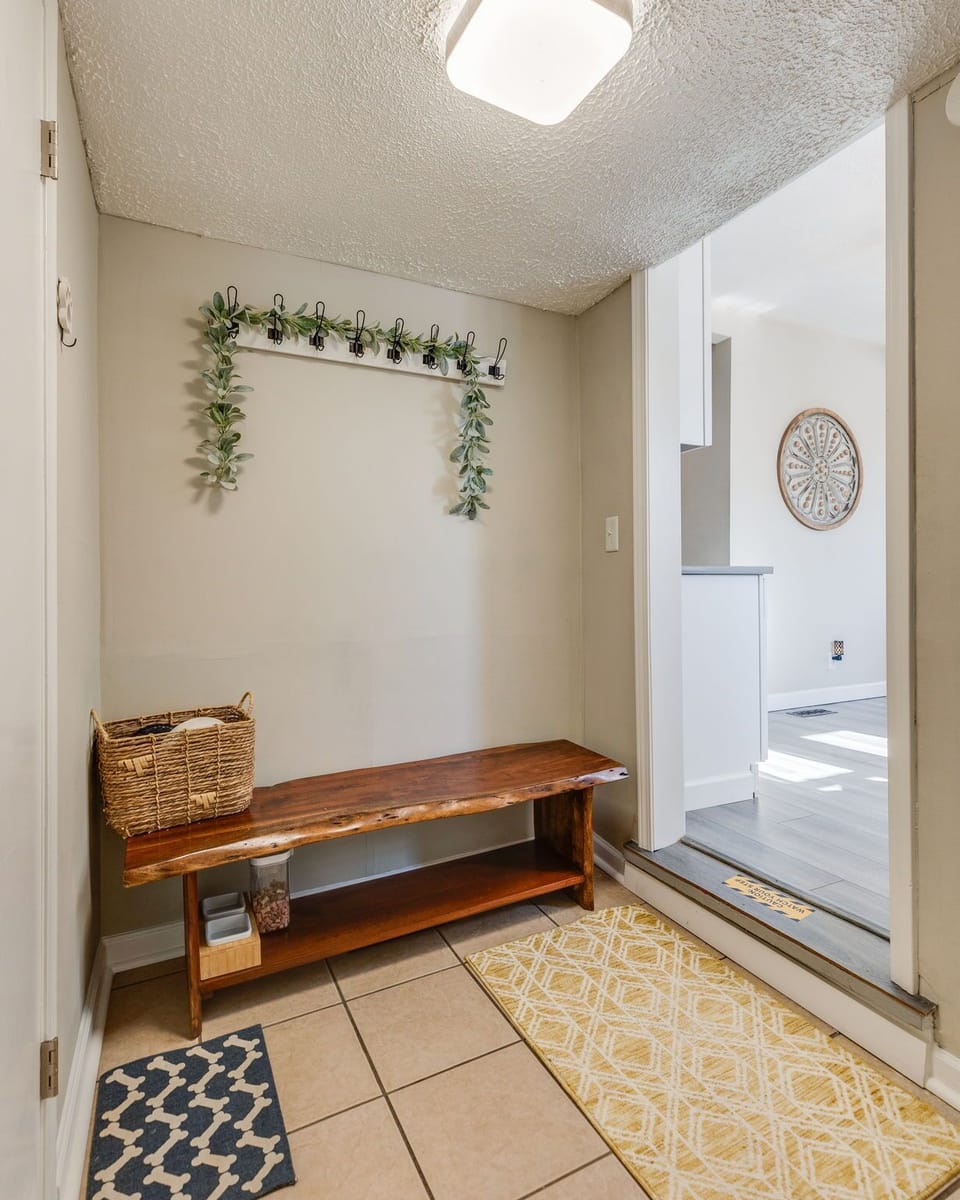 Welcoming mudroom entry with bench, hooks, and bright kitchen access.