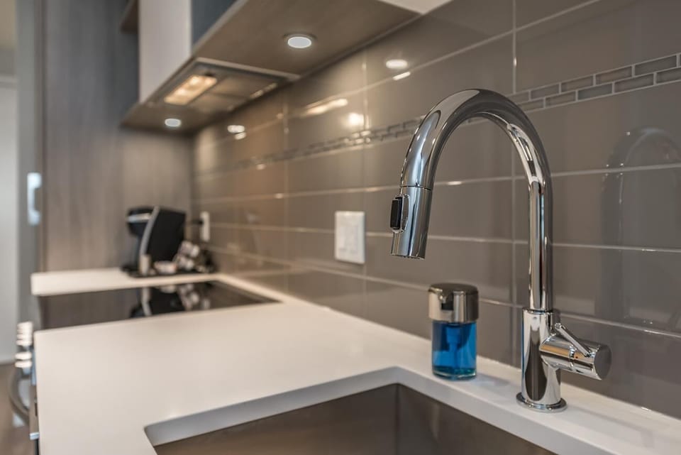 Detailed view of the kitchen food prep station, deep sink, and high-arc faucet fixture.