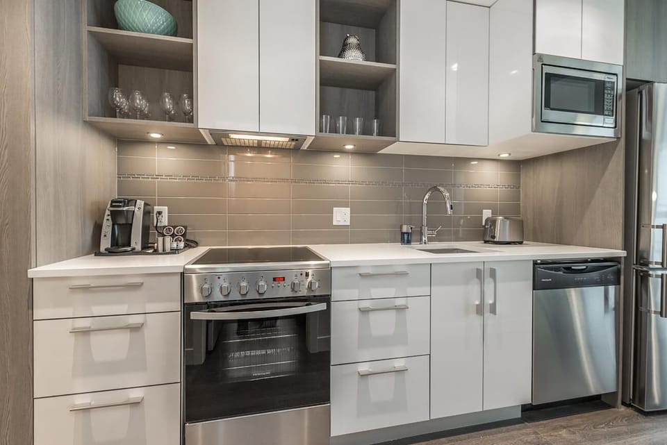 Fully equipped kitchen complete with full-sized stainless steel appliances, electric range, built-in microwave, and dishwasher.