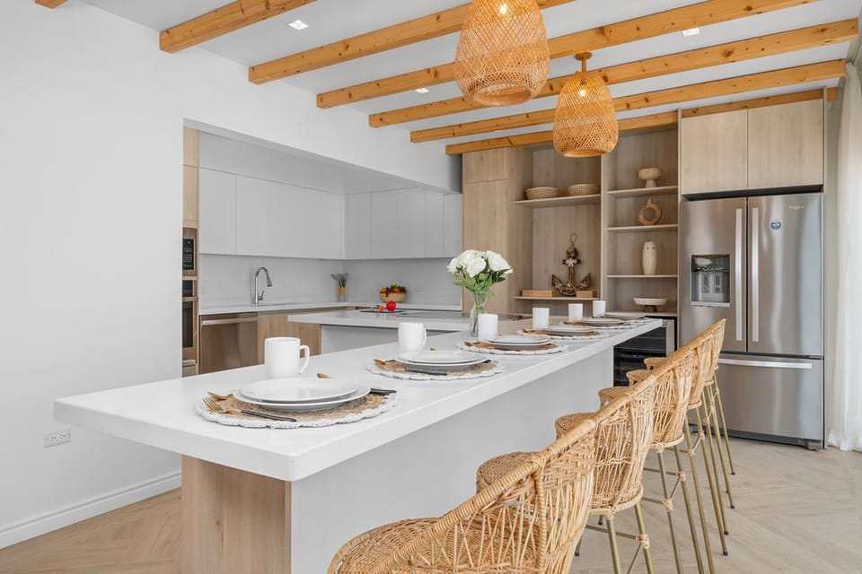 The dining area exudes modern elegance with a tropical twist, featuring a minimalist dining set with bold, natural textures.