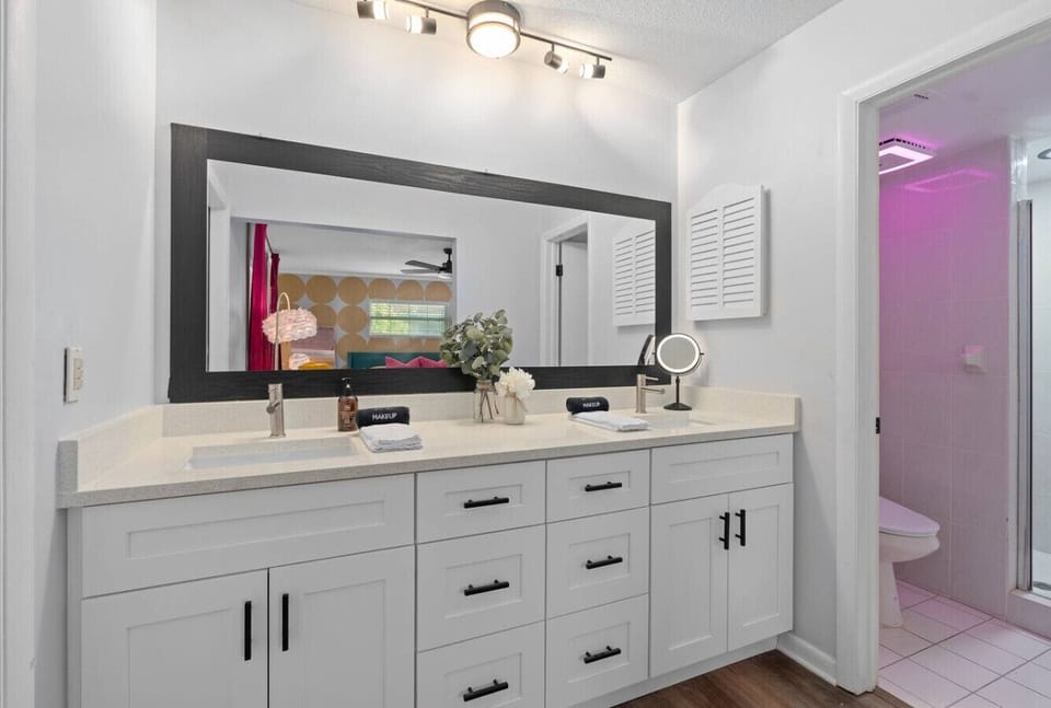 Sleek vintage-inspired bathroom with dual vanity, large mirror, retro pink accent wall and modern fixtures, Vivid Vintage Orlando