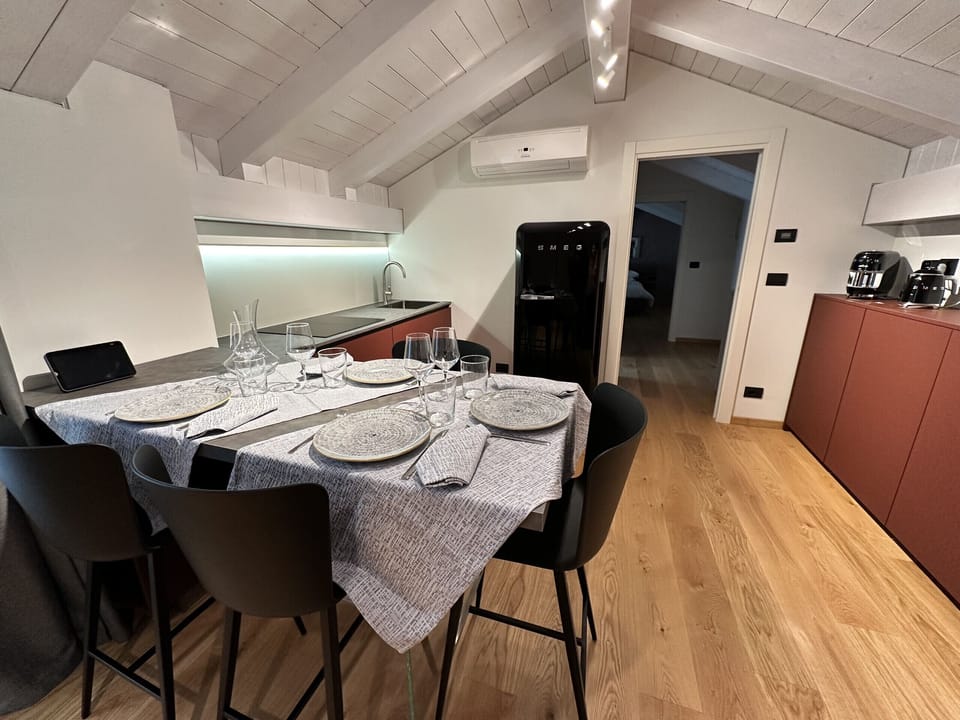 Kitchenette equipped with SMEG accessories, induction hob, combined electric and microwave oven, dishwasher, refrigerator, Lavazza pod coffee machine, kettle, crockery, dishes, glasses and cutlery.