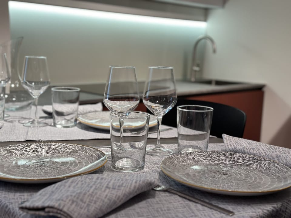 Kitchenette equipped with SMEG accessories, induction hob, combined electric and microwave oven, dishwasher, refrigerator, Lavazza pod coffee machine, kettle, crockery, dishes, glasses and cutlery.