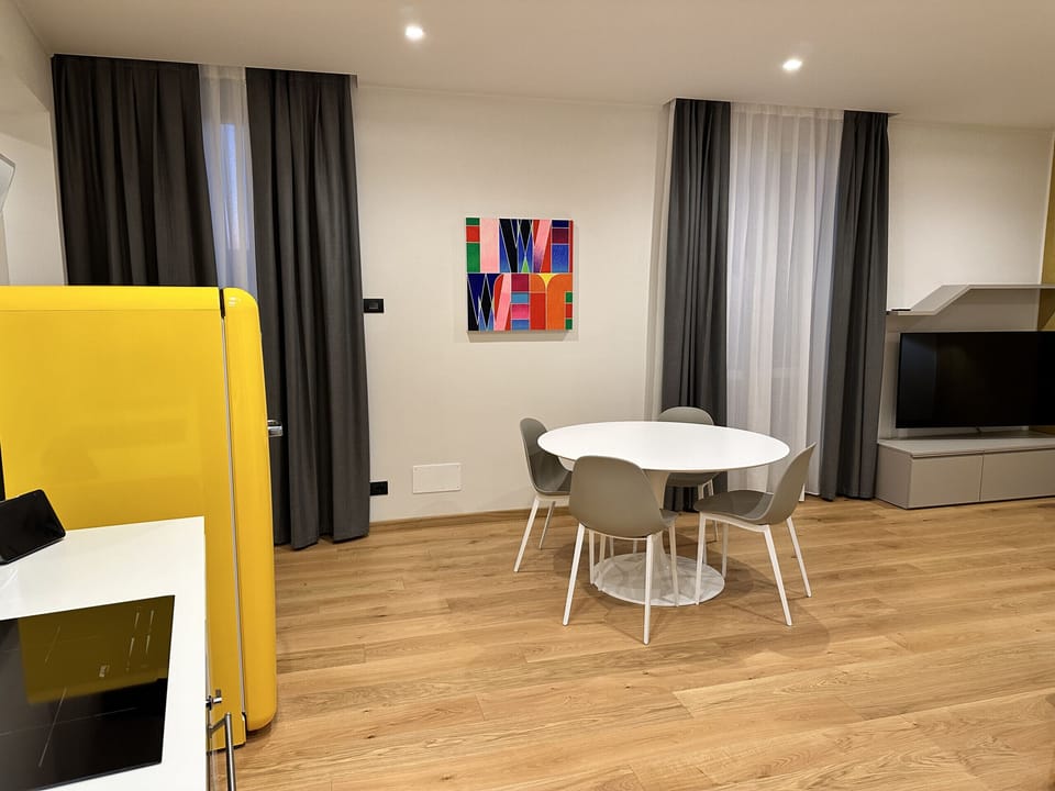 Spacious living room with kitchenette, round dining table with four chairs, sofa bed, balcony on Via Piol and SKY TV