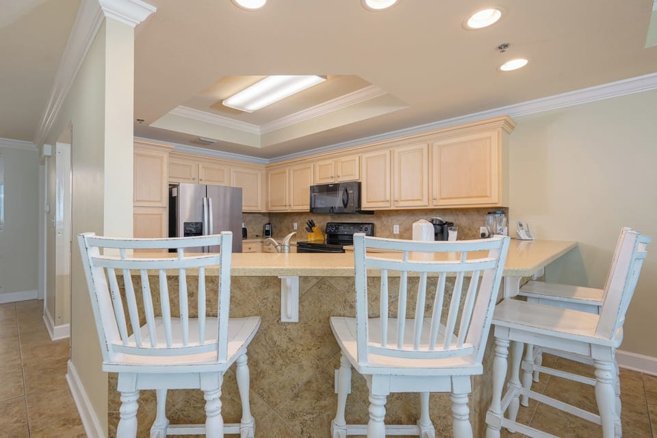 Gather around the breakfast bar with stylish stools, perfect for casual meals and conversation in this inviting kitchen space