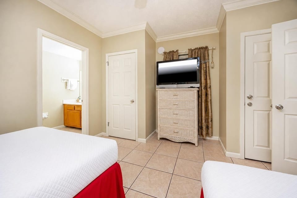 Inviting guest bedroom with two double beds, a TV, and easy access to a well-lit bathroom for your convenience