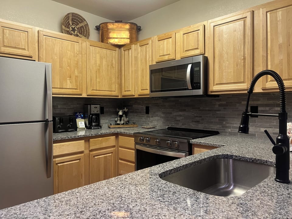 Your kitchen features granite counters, stainless appliances, and all the tools you need to prepare home-cooked meals. Warm wood cabinetry and modern fixtures create a welcoming space for gathering.