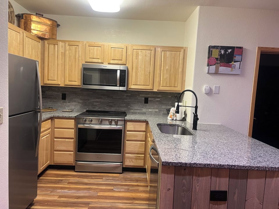 Your fully equipped kitchen features stainless steel appliances, granite countertops, and warm wood cabinetry—everything you need to prepare meals during your stay.