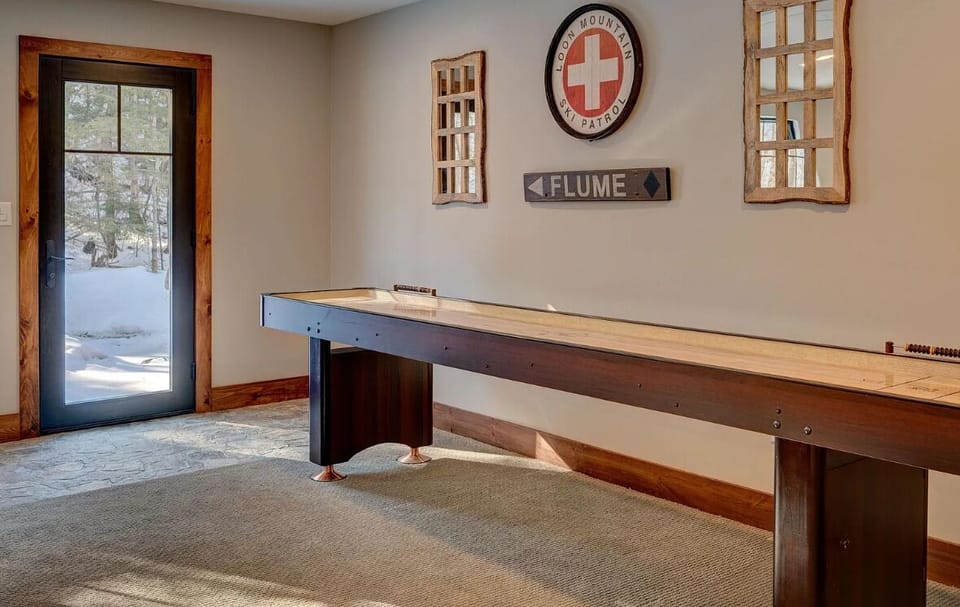 Enjoy some fun indoor entertainment with this sleek shuffleboard table, set in a bright space with mountain-inspired decor. Perfect for friendly competitions and relaxing afternoons.