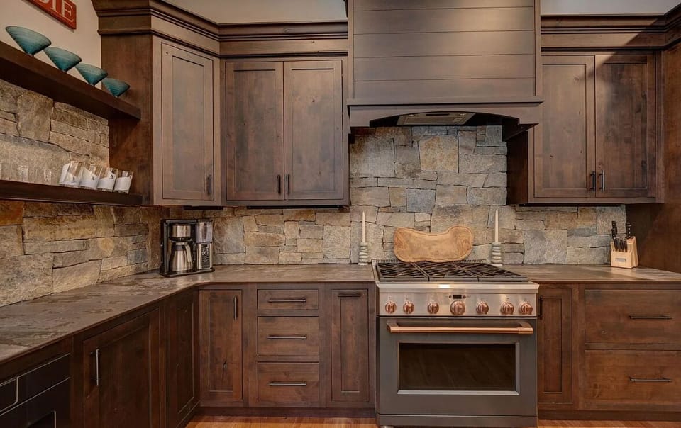 Beautifully designed kitchen with rich wood cabinetry, a stone backsplash, and a high-end gas range. The rustic elements and modern appliances create a perfect blend of style and functionality for all your cooking needs.