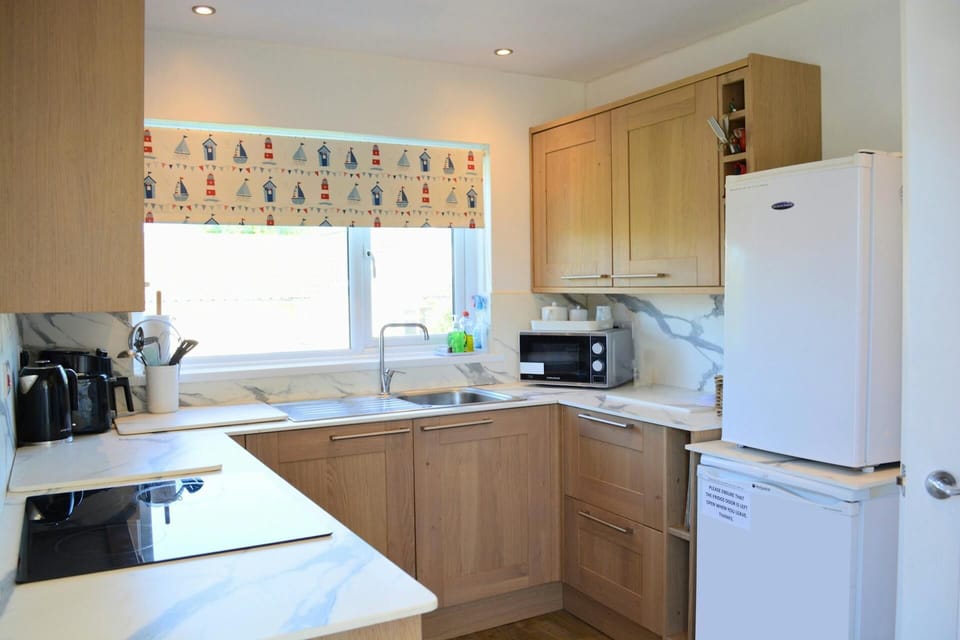 Built-in electric oven and hob, microwave, kettle, fridge, sink and kitchen cabinets