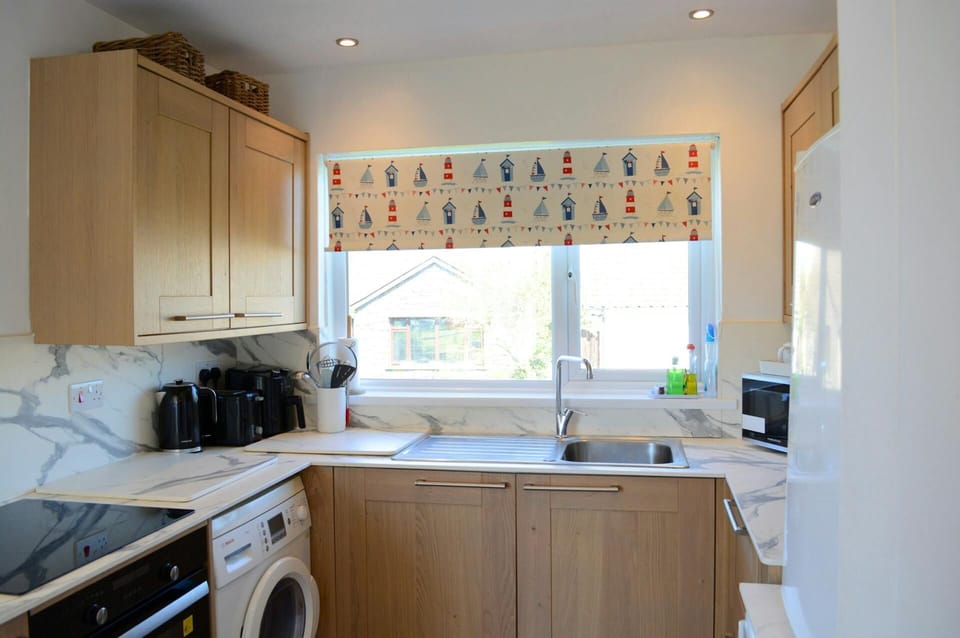 Cooker, microwave, toaster, fridge, sink and kitchen cabinets