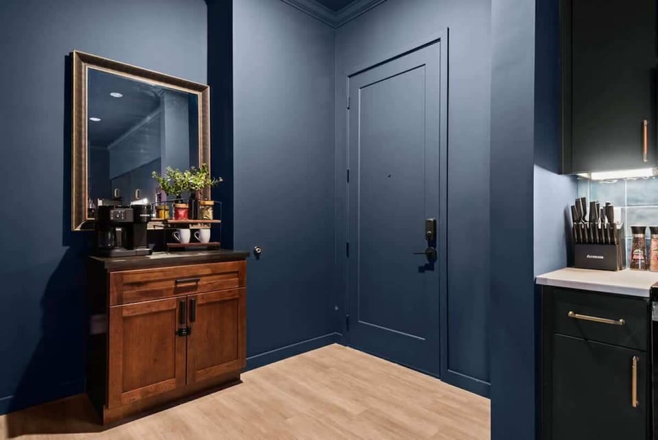 A stylish entryway featuring a coffee station and modern decor, with rich navy walls that create a cozy, welcoming atmosphere for guests.