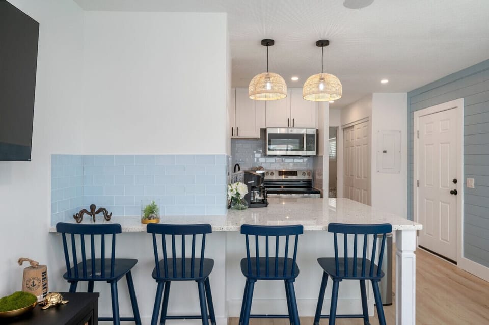 Bright and modern kitchen featuring sleek countertops, stainless steel appliances, and a cozy breakfast bar with stylish seating—perfect for enjoying meals and coffee!