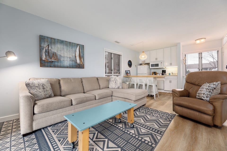 Spacious living room w/ plush sofa, patterned rug & open flow to the kitchen.