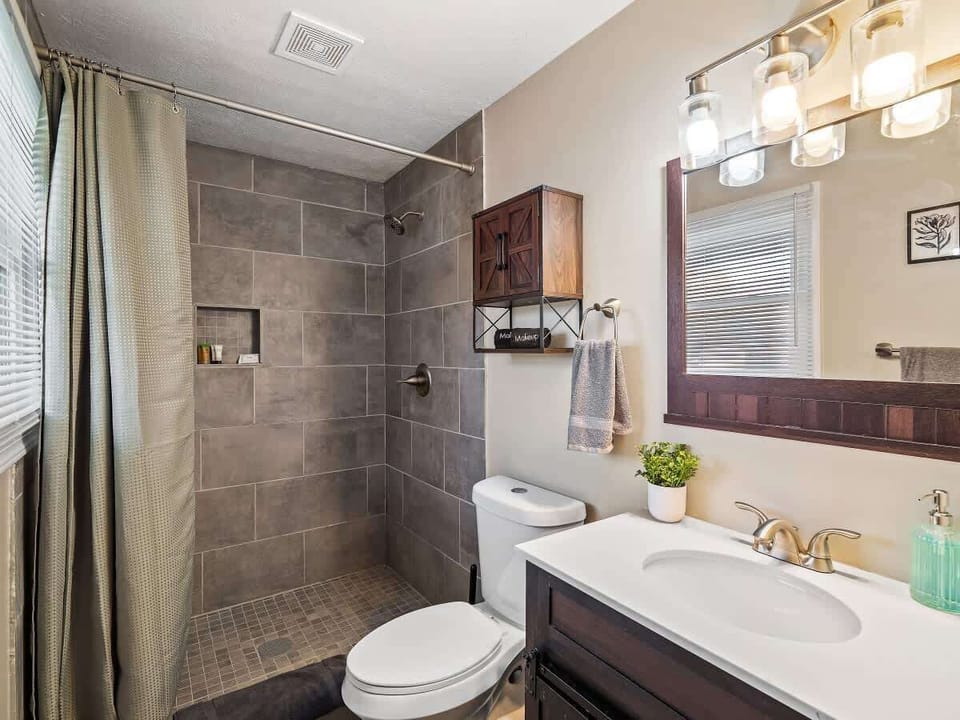 Bathroom w/ tiled walk-in shower, sink vanity & bright lighting
