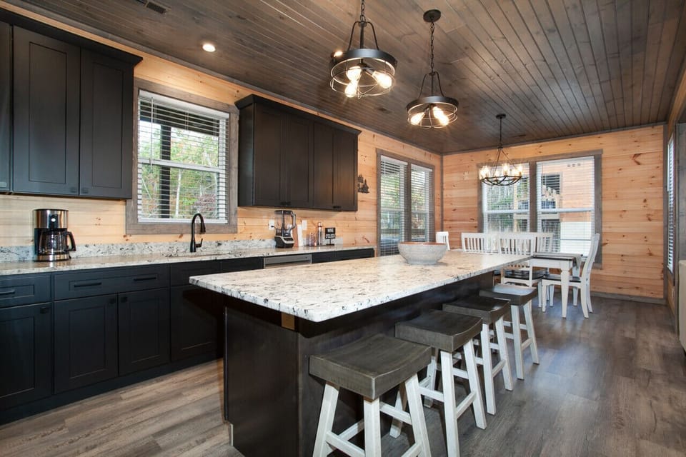 Modern cabin kitchen with black cabinets, granite counters, and wood accents.