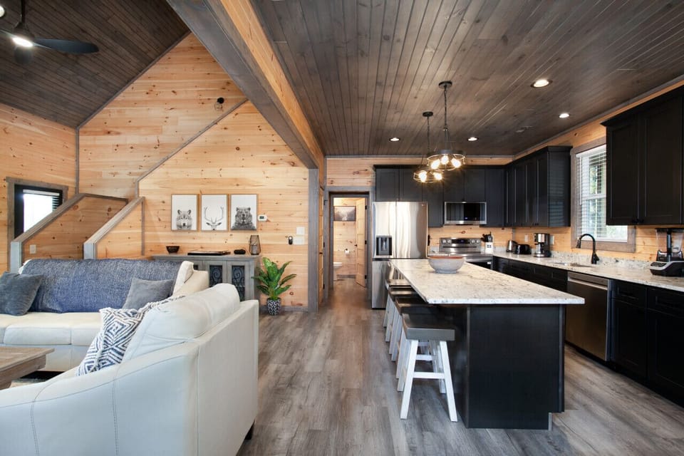 Spacious kitchen with dark cabinets, granite island, and open to living area