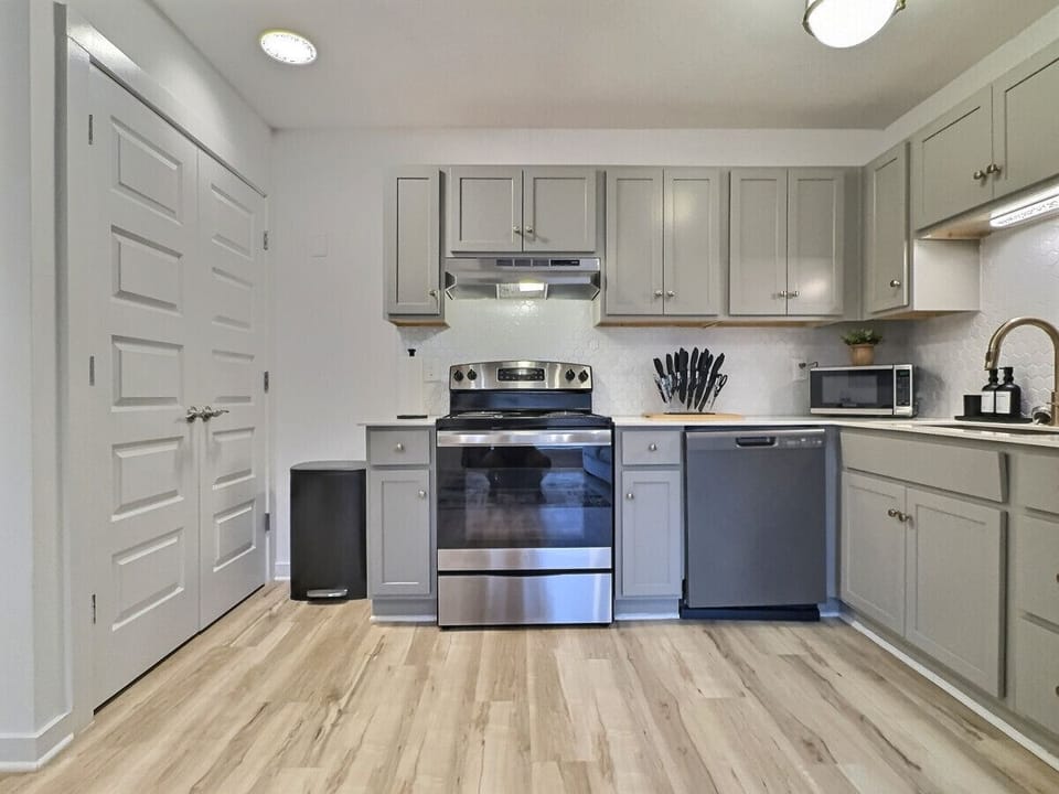 Modern kitchen with sleek stainless steel appliances and neatly arranged utensils, perfect for effortless cooking during your short-term rental stay.