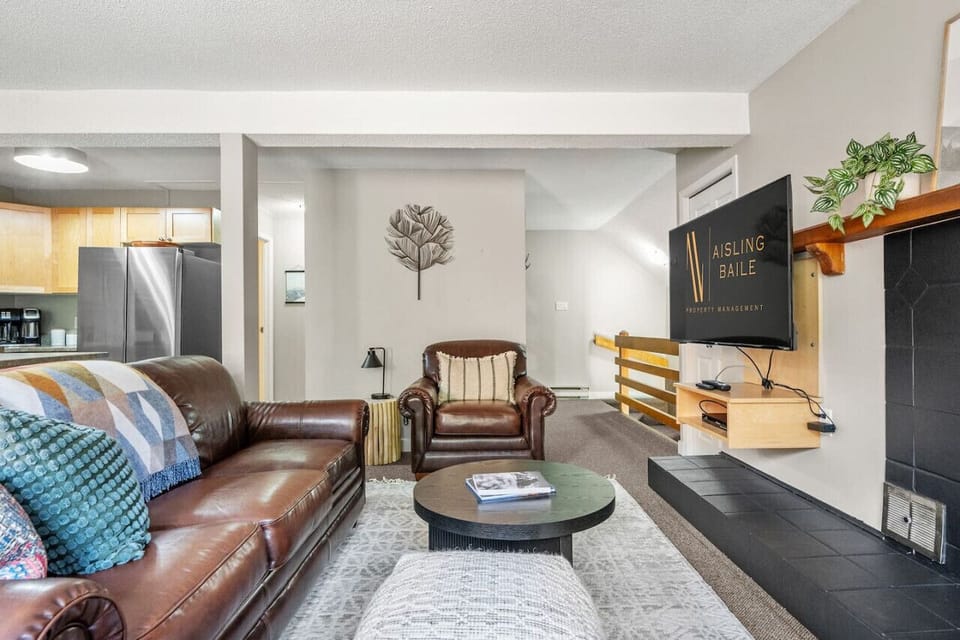 Living room with a smart TV with cable, a decorative fireplace, and cozy seating options with a queen-sized pull-out sofa bed.