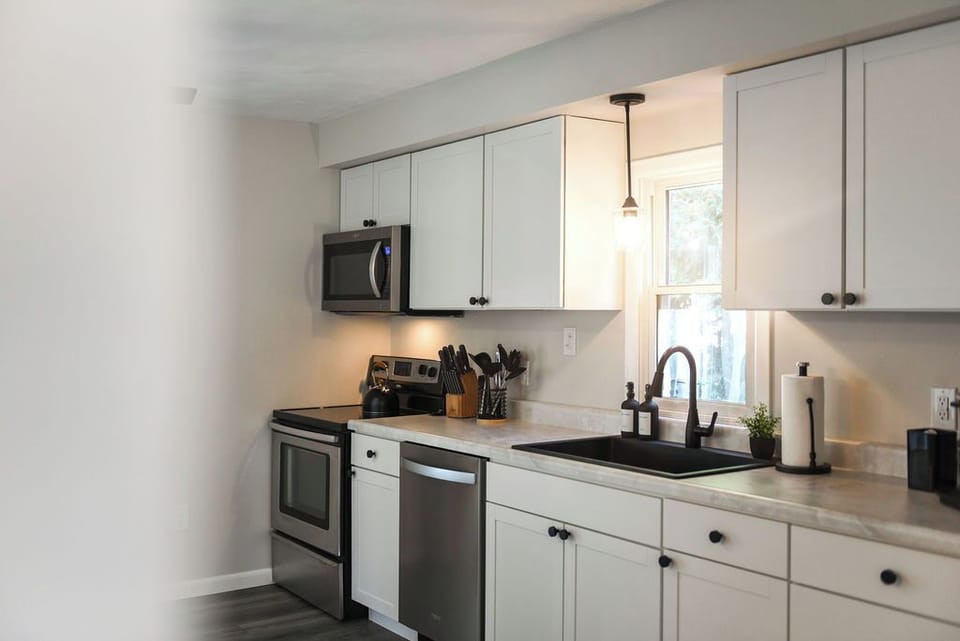 Modern and sleek kitchen with everything you need for a comfortable stay! Enjoy the stylish design, complete with stainless steel appliances, a large sink, and all the essentials for cooking and dining in.
