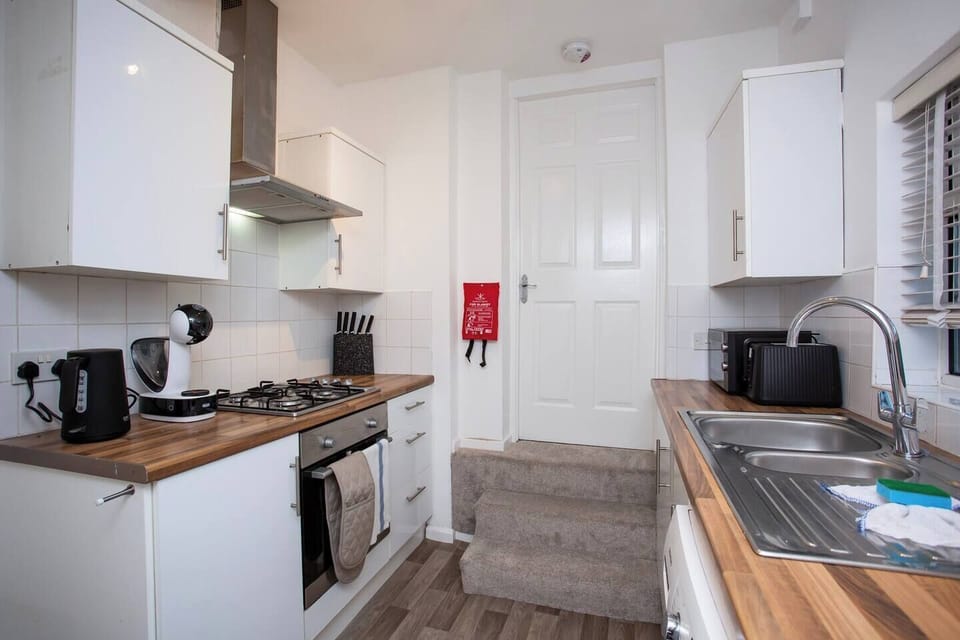 Fully equipped modern kitchen with sleek white cabinets, wooden countertops, and essential appliances. Compact, functional, and stylish.