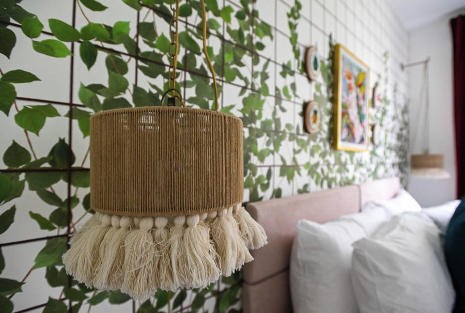 A beautifully styled boho pendant light set against a lush green leaf wall, bringing a serene, nature-inspired elegance to the bedroom.