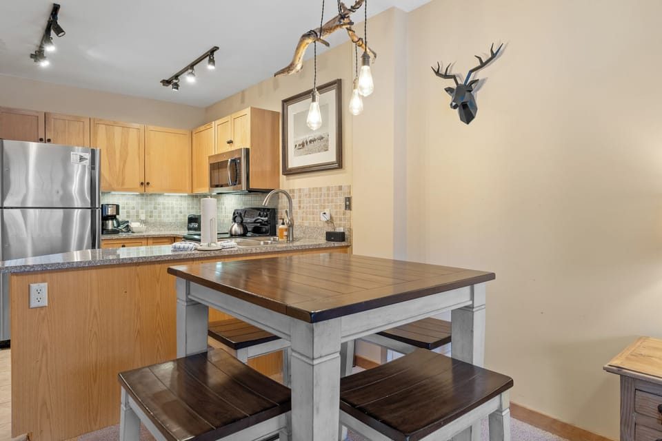 Gather around your rustic dining table in this cozy kitchen space, where warm wood tones and modern appliances create the perfect spot for morning coffee.