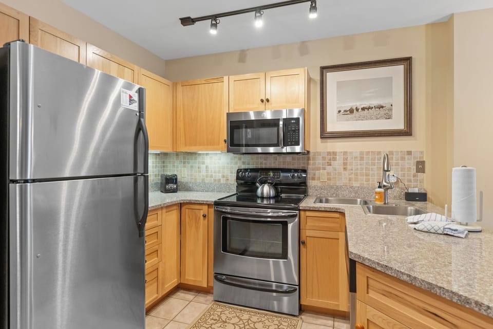 Your fully equipped kitchen features granite counters, stainless appliances, and warm wood cabinets—perfect for preparing meals during your stay.
