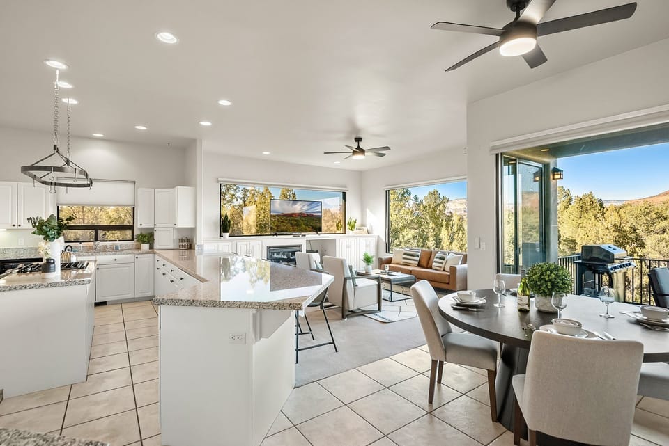 Living room with leather sofa, two chairs, open to kitchen and breakfast nook. Reflective 360 red rock view