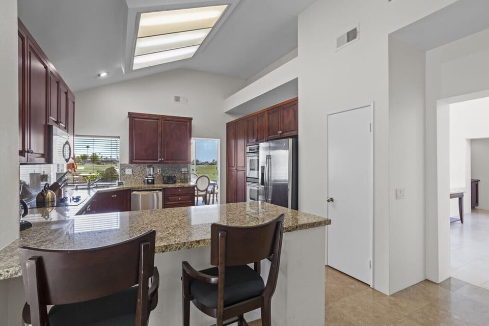Bright kitchen w/ large island, bar stools & skylights filling the space w/ natural light