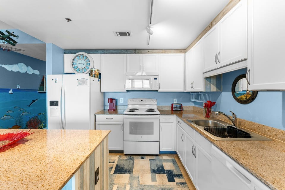 Bright kitchen with white cabinetry and a coastal blue accent wall.