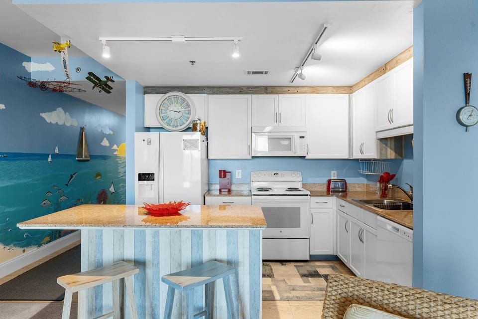 Cozy kitchen with white cabinetry and a striped breakfast bar overlooking a playful mural.