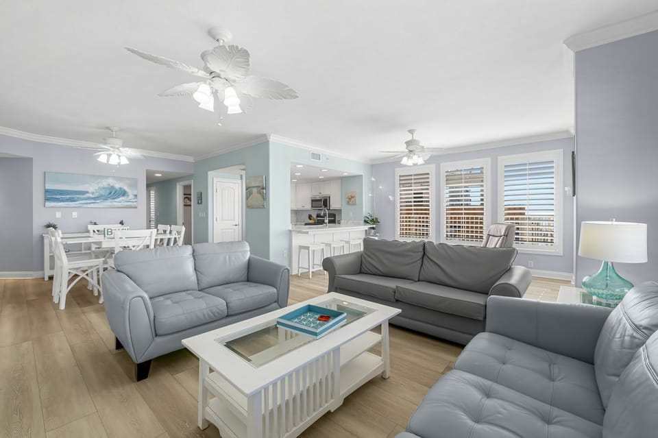 Spacious living room with modern gray sofas and natural light from large windows.