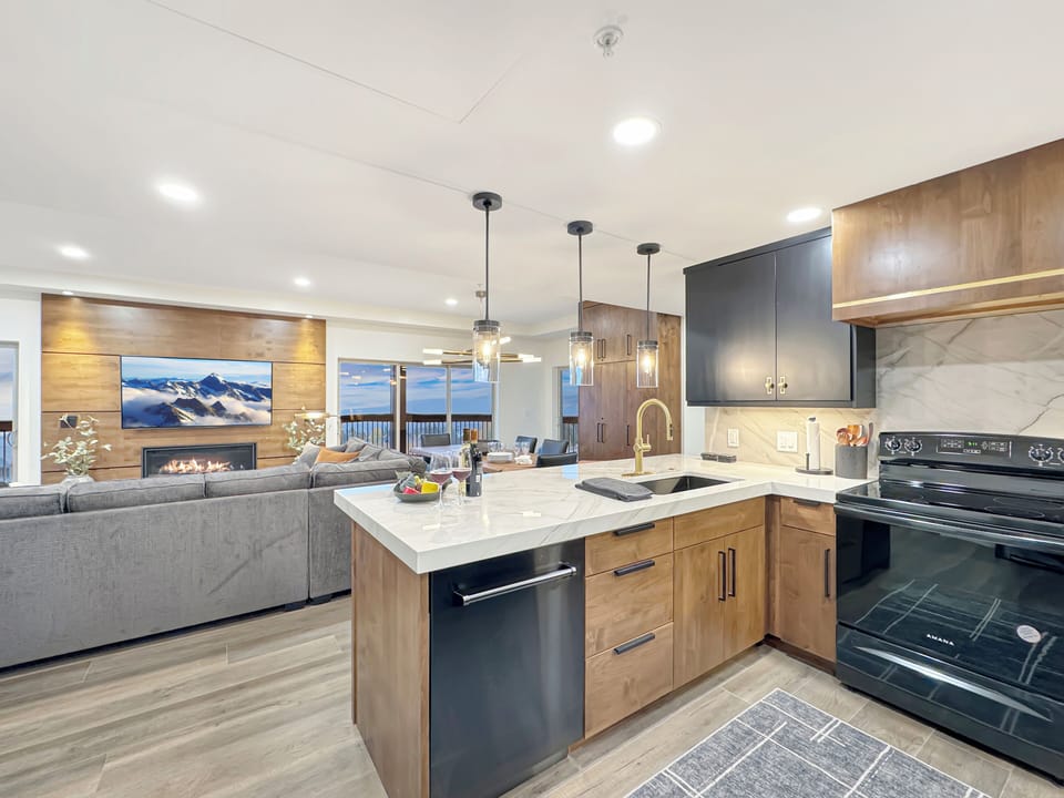 The A suite common area boasts a fully stocked, gourmet kitchen, a dining table with seating for 10 and seating for 3 at the bar, a gorgeous gas fireplace, and a private balcony with sweeping views.