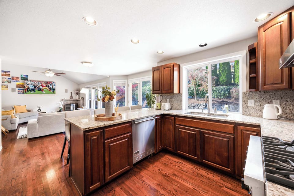 Enjoy cooking in a kitchen that offers a beautiful view of the landscaped backyard. The granite countertops, modern appliances, and cozy seating area nearby make this space ideal for culinary creativity and socializing.